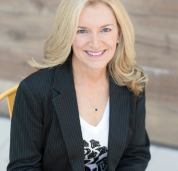 Seated smiling executive wearing necklace and blazer