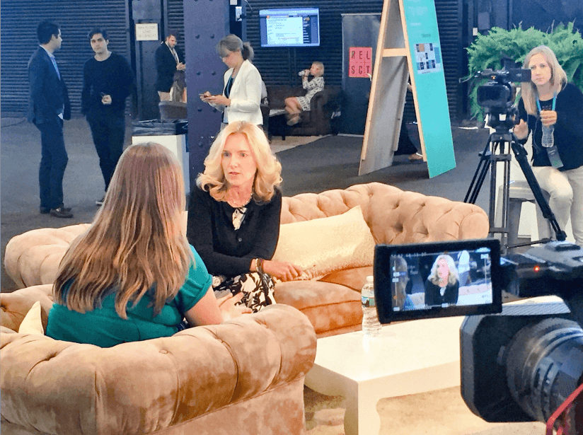 Two women engaged in a conversation on a cozy couch in a studio setting.